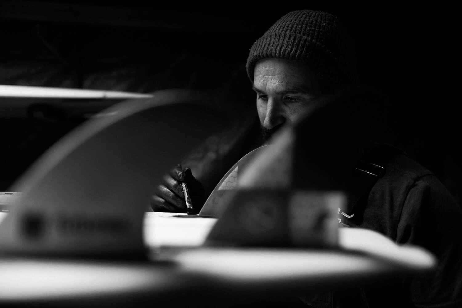 A person working intently on a project in a dimly lit environment, with focus and concentration evident in their expression.