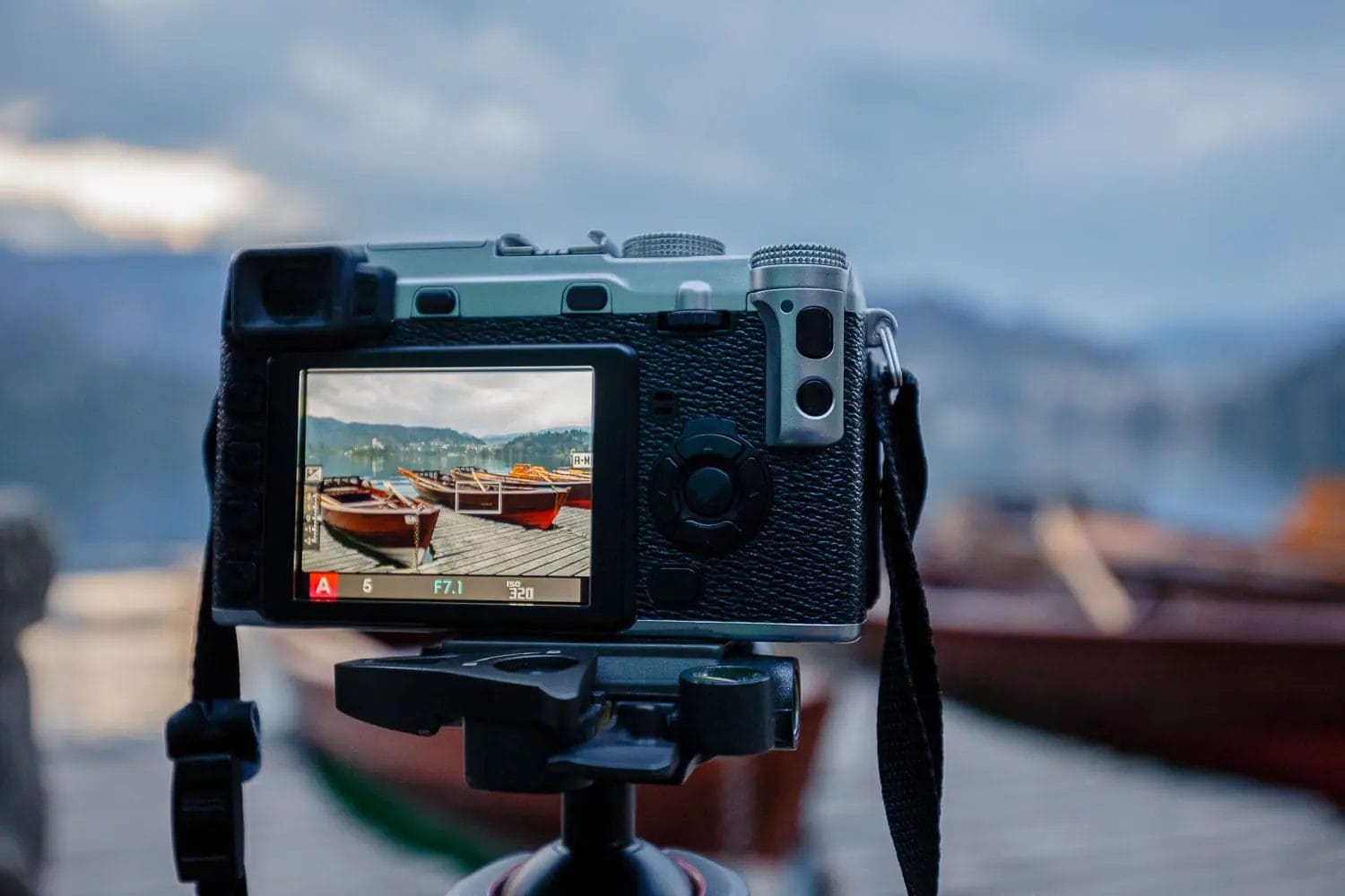 Camera on a tripod capturing a scenic view of boats on water.