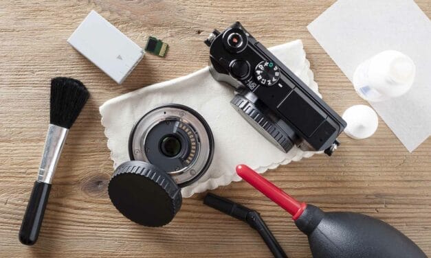 Camera cleaning equipment and a disassembled lens on a wooden surface.